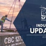 UTC Overseas Industry Update August 2022 (white UTC logo and text over semi-transparent dark blue overlay). Background image: pink & purple sky in background, four men in reflective vests are on the back of a ship. two men stand aside while two men are adjusting a piece of equipment being loaded onto ship.