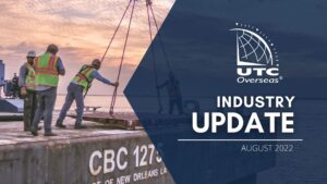 UTC Overseas Industry Update August 2022 (white UTC logo and text over semi-transparent dark blue overlay). Background image: pink & purple sky in background, four men in reflective vests are on the back of a ship. two men stand aside while two men are adjusting a piece of equipment being loaded onto ship.