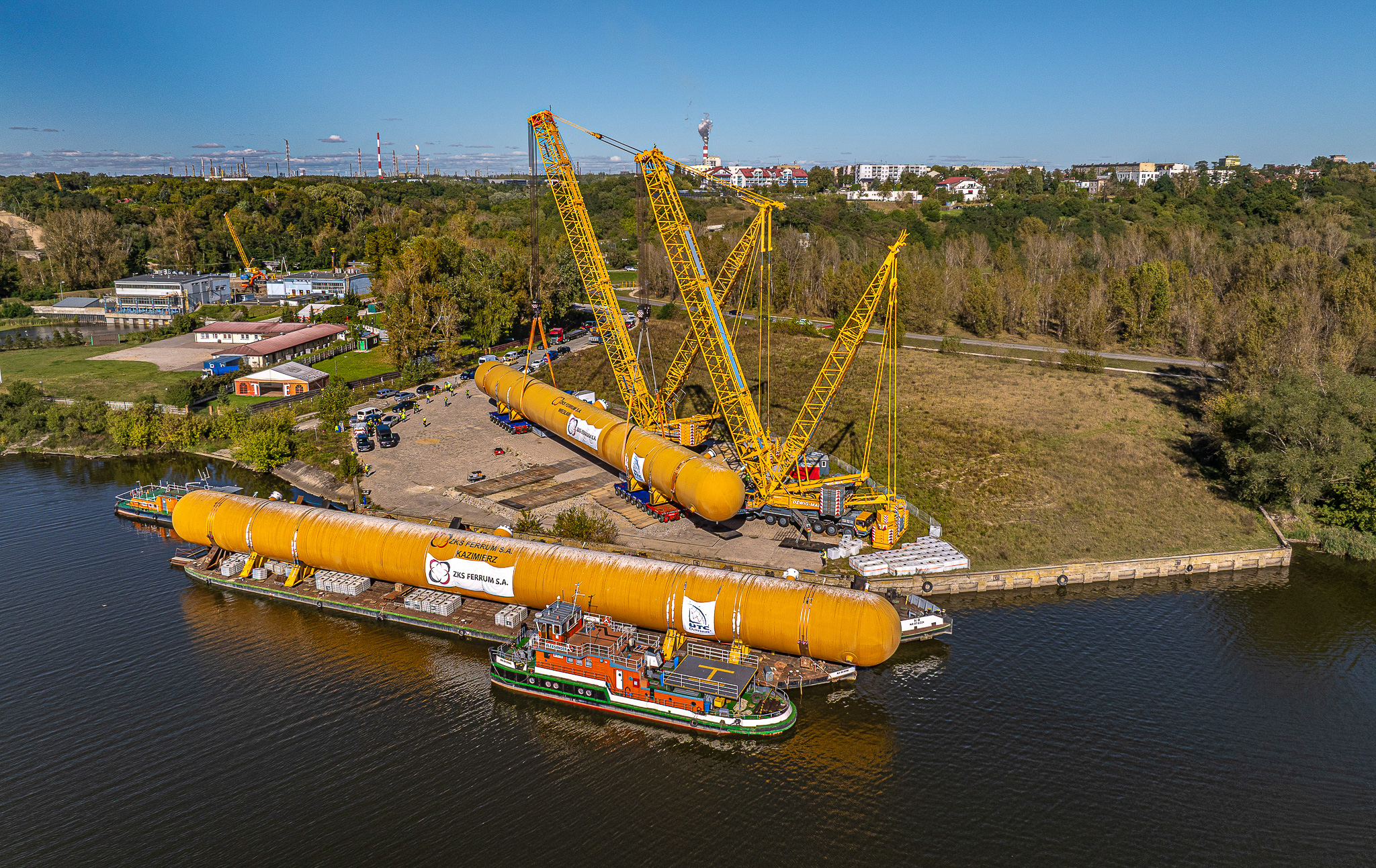 Twin crane lift transferring oversized LPG storage tank from barge to transport platform