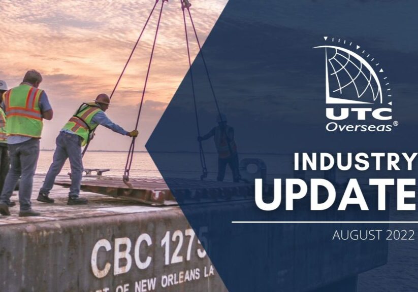 UTC Overseas Industry Update August 2022 (white UTC logo and text over semi-transparent dark blue overlay). Background image: pink & purple sky in background, four men in reflective vests are on the back of a ship. two men stand aside while two men are adjusting a piece of equipment being loaded onto ship.